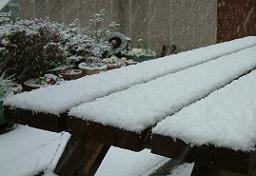 Click for larger image (1,500×1,024) Snow on picnic table not thick enough to cover gaps between planks.