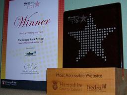 Click for larger image Trophy has wooden block base for translucent glass panel engraved with large Hantsweb Awards logo. Certificate is signed by Leader of Hampshire County Council and says: “Winner, Most accessible website, Calthorpe Park School.”