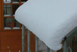Bizarre snow drift had slipped down the greenhouse roof.