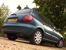 Photo from ground level at crooked angle showing rear of the car and reflections down the side.