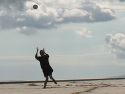 Me throwing and catching the ball, dwarfed by endless sand.