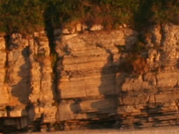 Low orange sunlight striking the intricate steps and strata of low cliffs.