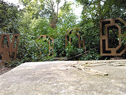 “Woods” spent out in modernist carved wood with a rough block of stone in the foreground.